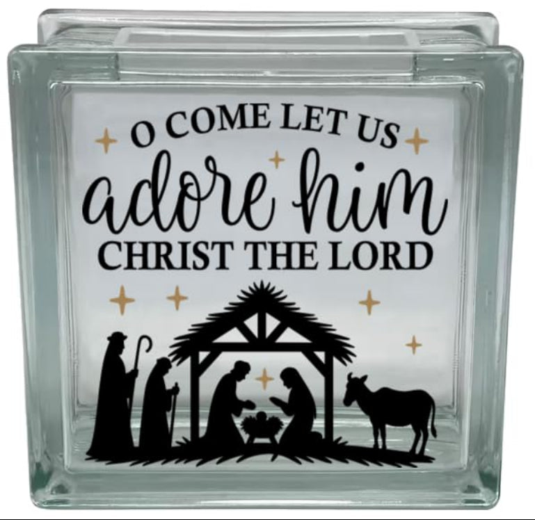 Glass block with nativity scene and text 'O Come Let Us Adore Him Christ the Lord' on a white background