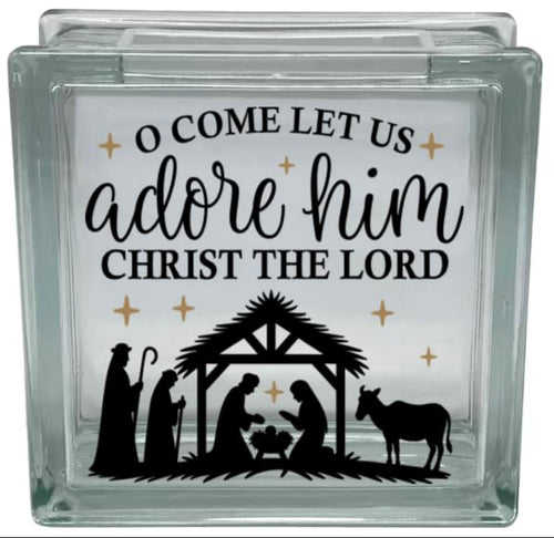 Glass block with nativity scene and text 'O Come Let Us Adore Him Christ the Lord' on a white background